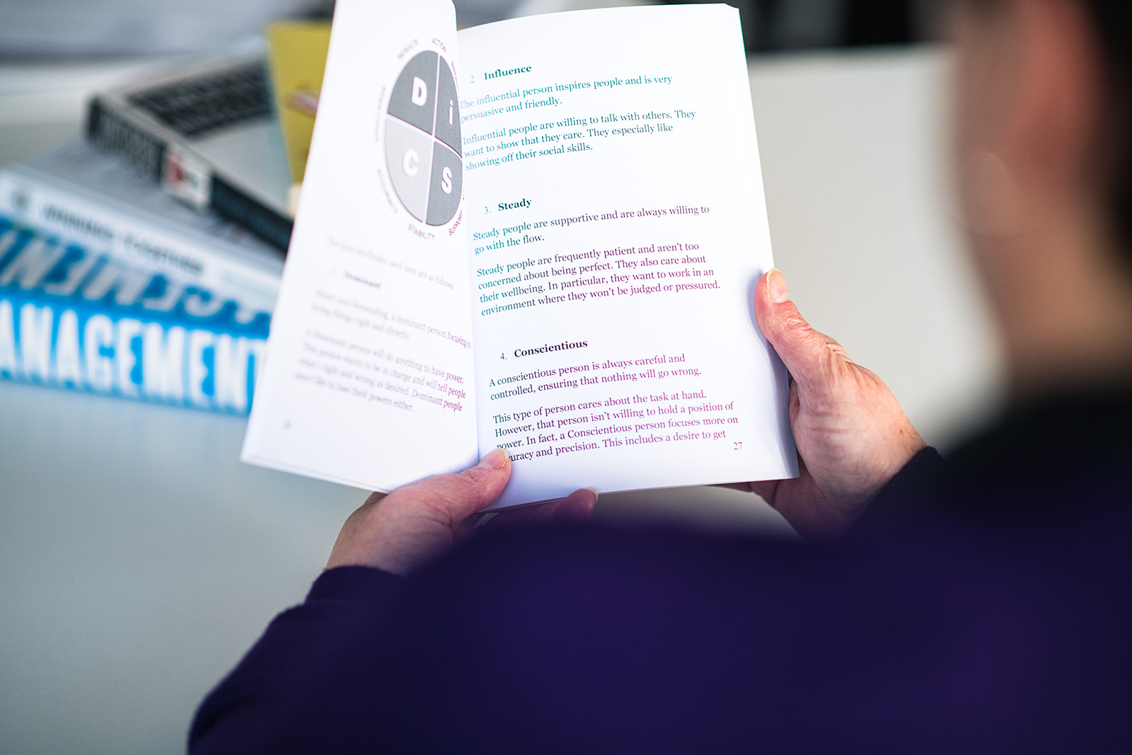Joanne reading a book about DiSC to understand how and why the same problems keep repeating at work